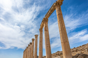 Ancient columns at the archaeological site of Jerash. Jordan. Blue sky with clouds in the background.  There is enough space for your use in the photo.