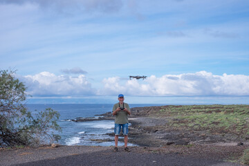 Front view of active man driving drone flight on sea cost. People and weekend tourism leisure outdoor activity concept lifestyle. Ocean and southern coast of Tenerife,the Punta Rasca natural park