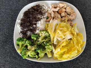 Homemade grilled chicken with rice and broccoli, served on a white plate