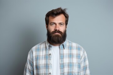 Fototapeta premium A man with a beard and plaid shirt poses for a photo.