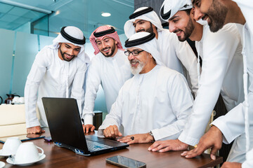 Group of corporate arab businessmen meeting in the office - Business people wearing emirati clothing  working in the office - 733263331