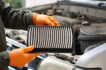 Closeup mechanic's hands hold air filter pad of car engine to check. Concept, car broken,repair and maintenace service. Dirty air fillter need to change for hygienic.     