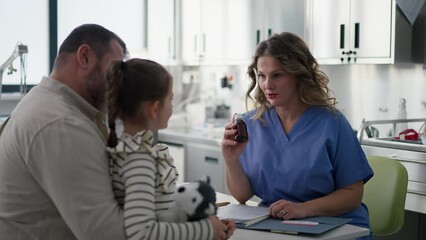 Doctor explaining test results to father of young girl patient. Concept of children healthcare and emotional support for child patients.