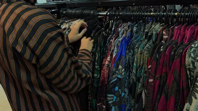 A man is choosing batik at a local batik shop in Indonesia