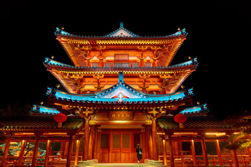 Chinese temple with roof at night with a lady in sight