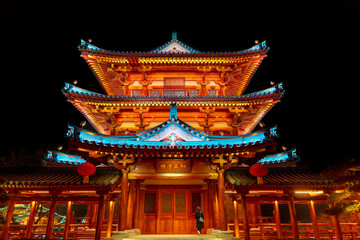 Fototapeta premium Chinese temple with roof at night with a lady in sight