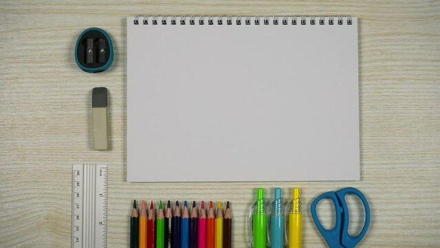 Set of school stationery supplies. Blank notebook, colored pencils, pens, scissors, ruler, pencil sharpener and eraser on wooden desk. Back to school concept