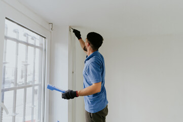 A young oriental man paints a wall with a brush.