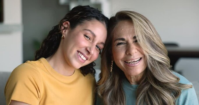 Close up portrait laughing mature mum and young daughter looking at camera, feel happy, enjoy spending time together, showing sincere love and harmonic relationships. Hispanic relatives women portrait