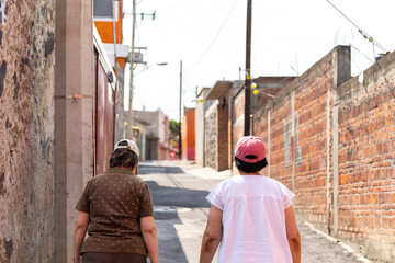 Mujeres con gorra caminando en un callejon de un pueblo
