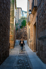 Fototapeta na wymiar Female tourist strolling through the narrow streets of the medieval town of Caceres, Spain.