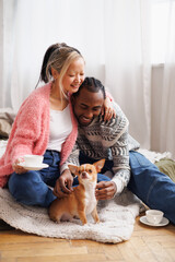 Positive asian woman with coffee hugging african american boyfriend near pet in bedroom