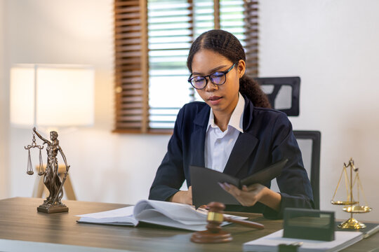 Portrait of young female Lawyer or attorney working in the office, analyzing data, reading contract documents work with law books hammer of justice Consulting lawyer concept.