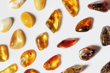 Amber stones at sunlight on light background, minimal style pattern from transparent stones in...