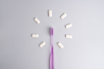 Toothbrush and chewing gum lie on a colored background. Time to brush your teeth. Top view, flat lay. Dental health concept