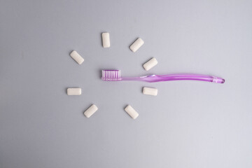 Toothbrush and chewing gum lie on a colored background. Time to brush your teeth. Top view, flat lay. Dental health concept
