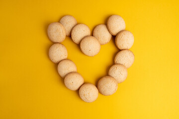 Heart shaped cookies decorated for Valentine's Day on a yellow background. Free space for text. Sweet snack