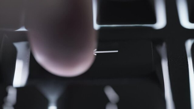 Pressing backspace key with a a finger several times on black computer keyboard. Close up. 