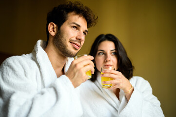 Couple relaxing with fresh juice in spa robes