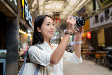 Travel woman use digital camera to take photo in the street market