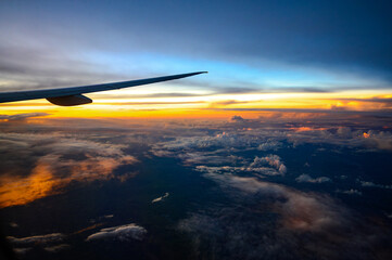 Nuvens laranja e céu azul profundo no final da tarde a partir da janela do avião na região entre...