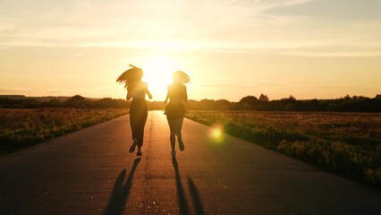 two friends running sunset, team group girls running sunset, silhouette athletic girls, teamwork...