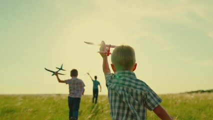 Children play run with toy airplane in their hand sunset. Boy child plays airplane pilot. Dream...