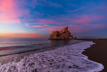 Playa Peñon del Cuervo, beach in the city of Malaga with a rock formation that divides the beach in two, located in the eastern part of the city, Costa del Sol. - obrazy, fototapety, plakaty