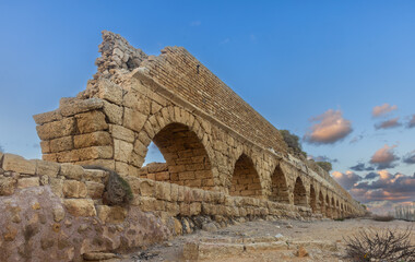 Aqueduct built by the Romans against the sky at sunset in Caesarea Israel