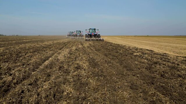Agricultural Ukraine. Tractors working in the field. Farmers cultivating black soil.