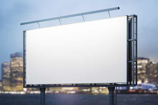 Blank white billboard on cityscape background at evening, perspective view. Mock up, advertising concept