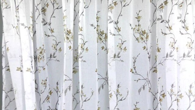 Waves of the white tulle curtain are falling in motion. The fabric is delicate and thin airy for the window.