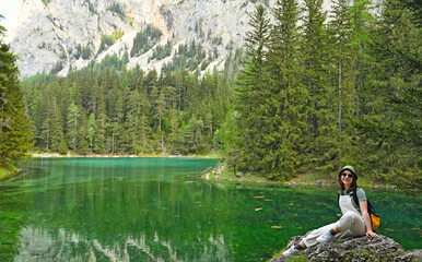 a girl sits on a rock and enjoys nature  on Green lake Styria Austria