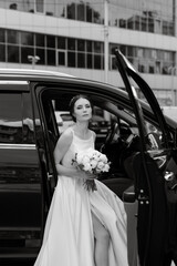 bride with a black car near a glass skyscraper