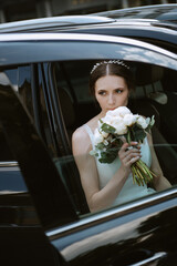 bride with a black car near a glass skyscraper