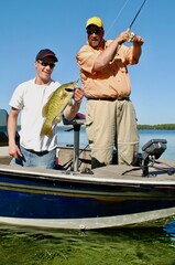 A pair of anglers netting a smallmouth bass