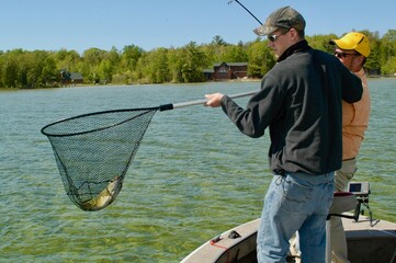 A pair of anglers netting a smallmouth bass 