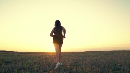 Free young woman runs in spring in park at sunset. Active healthy girl is engaged in fitness,...