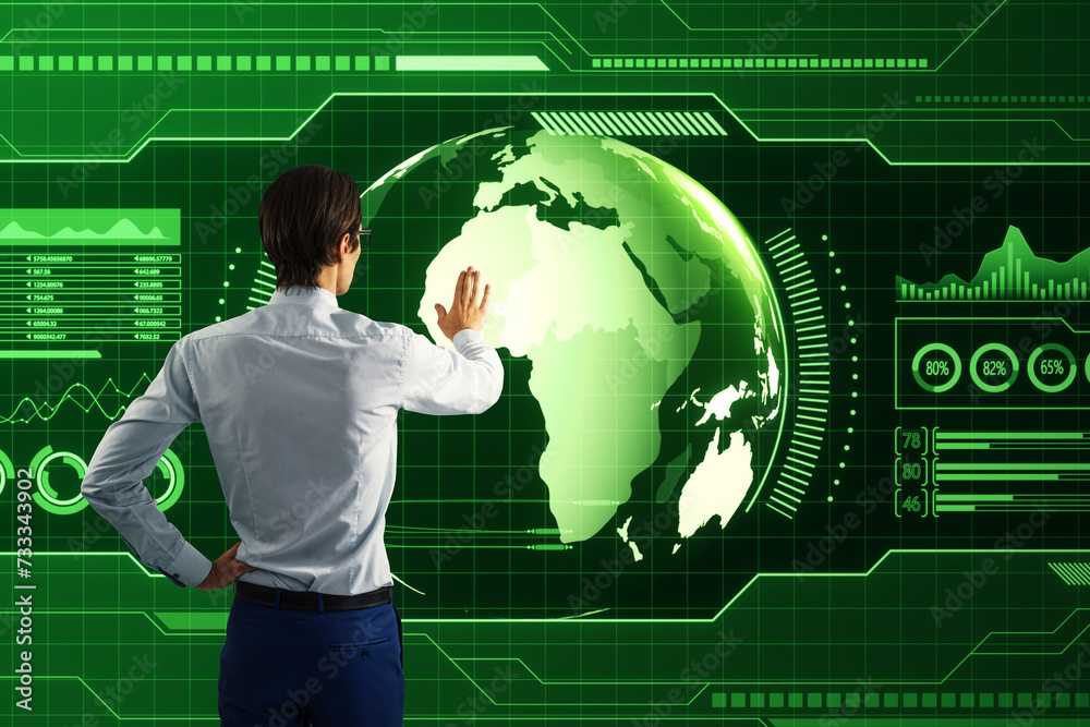 Aufkleber Back view of businessman using holographic screen with digital globe interface and business chart on blurry green background. HUD, international stock and future monitor concept.
