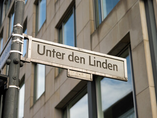 Fototapeta premium Unter den Linden street in Berlin. Sign with the road name at an intersection. The location is popular as boulevard in the capital city of Germany. It is named after the linden trees.