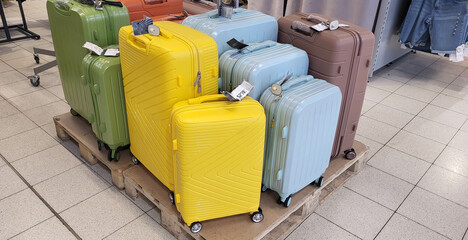 Beautiful multicolored travel suitcases are on a pallet in the store.