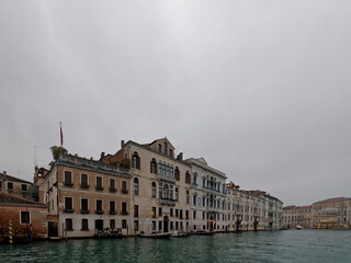 Facades of weathered buildings with windows on street of Venice city near canal water in daylight