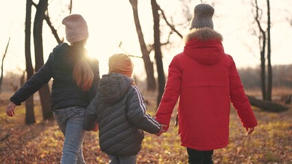 kids walk in the forest in autumn park. happy family kid dream concept. a group of children nature holding hands in jackets in the fall walking in park in forest lifestyle. freedom childhood concept