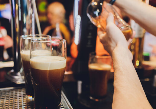 Barkeeper pulling a pint of beer behind the bar.