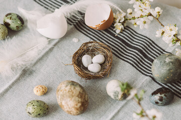 Fototapeta na wymiar Stylish easter eggs and cherry blossom composition on rustic table. Happy Easter! Modern natural dyed marble eggs and spring flowers. Rural still life