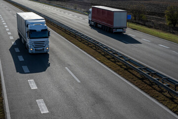 
Two trucks are driving in opposite directions on the highway. Large trucks for transporting goods...