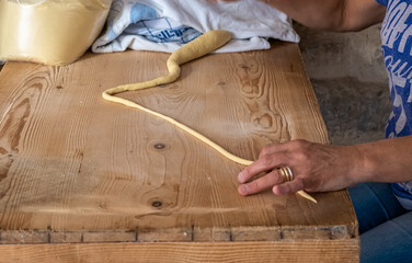 Close up on the hands of a woman preparing orecchiette, the typical apulian pasta, on the street in the historic center of Bari, Puglia region, Italy