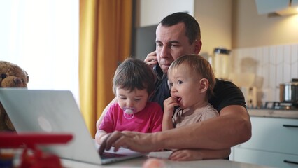 father working from home a remotely with two baby in his arms. pandemic remote work business...
