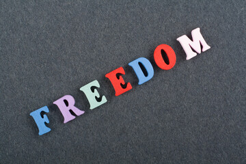 FREEDOM word on black board background composed from colorful abc alphabet block wooden letters,...