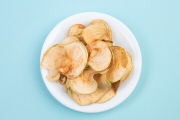 Sliced, dried apples in a plate isolated on blue background. Homemade organic apple.